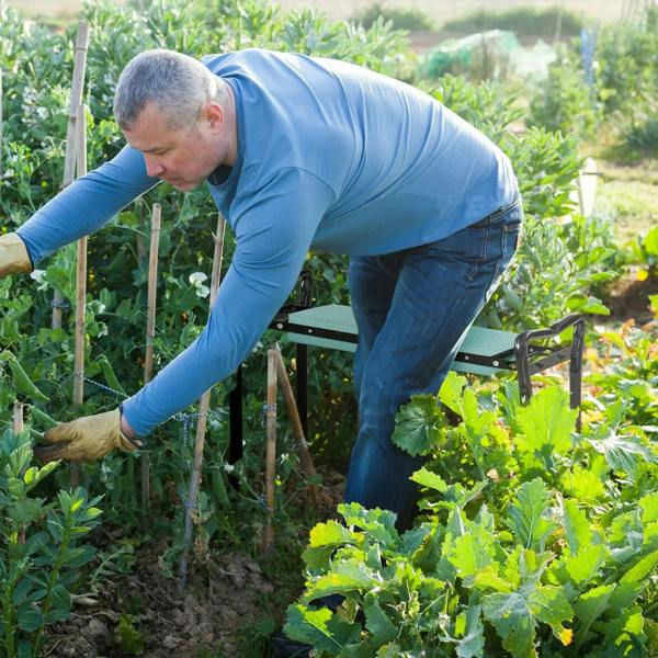 Person using a garden kneeler seat with dark green cushion while tending plants