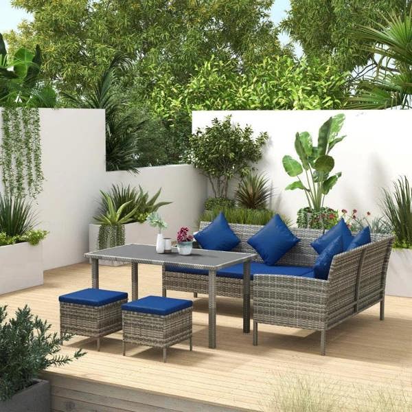 Rattan outdoor lounge dining set with dark blue cushions, table, and two matching ottomans