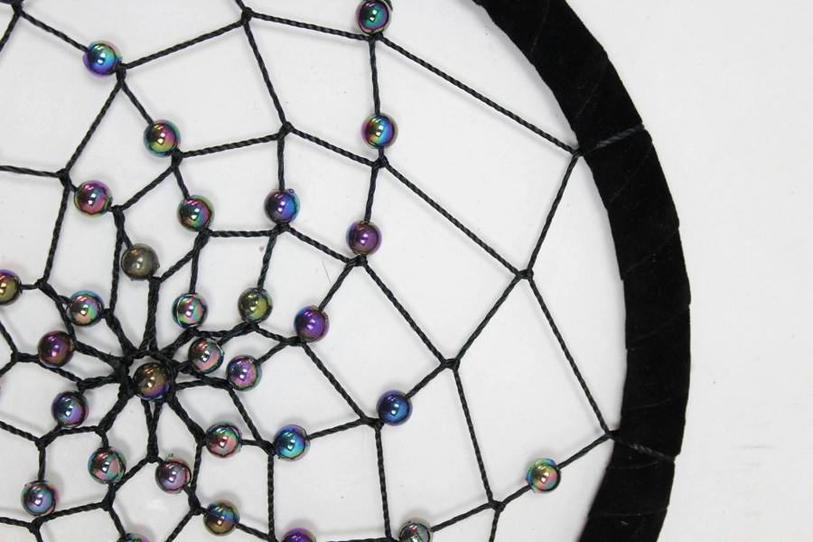 Close-up of dreamcatcher web with multicolor bead accents on black thread