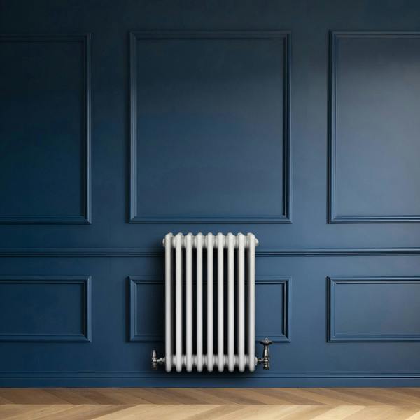 Traditional white 4 column radiator with valves, mounted against a deep blue wall, showcasing a sleek, modern design and smooth finish