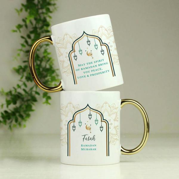 A personalised ceramic Ramadan mug with a metallic gold handle printed with "Farah Ramadan Mubarak" inside a teal and gold arch.