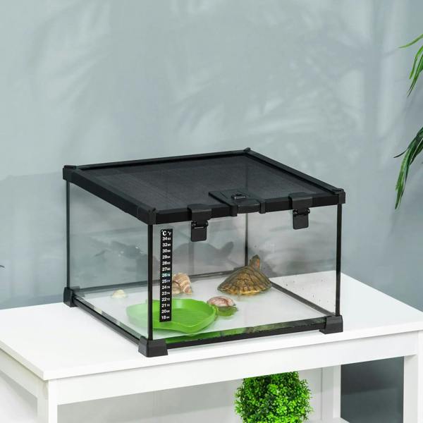 Black glass terrarium tank with green water basin and thermometer strip near rocks