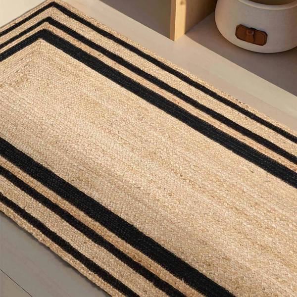 Beige rug with black stripes on a light wooden floor.