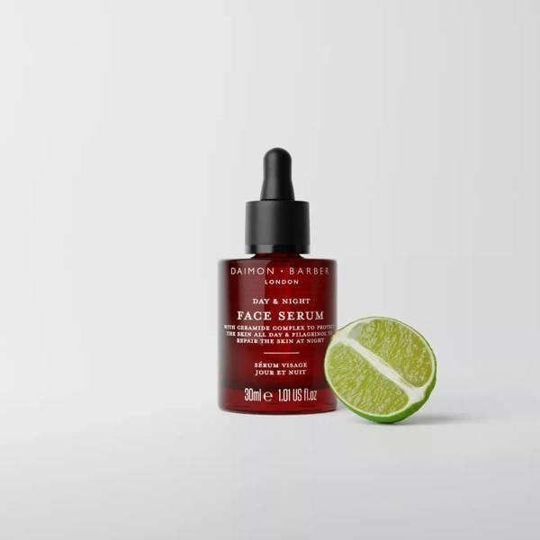 Daimon Barber red face serum bottle with dropper next to a lime wedge on a white background