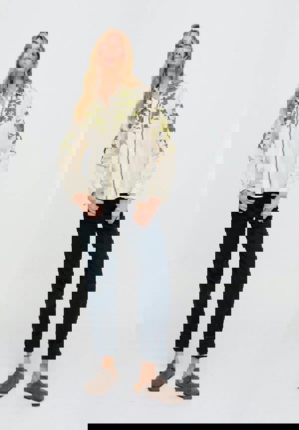 Woman wearing a floral shirt and dark pants on a white background