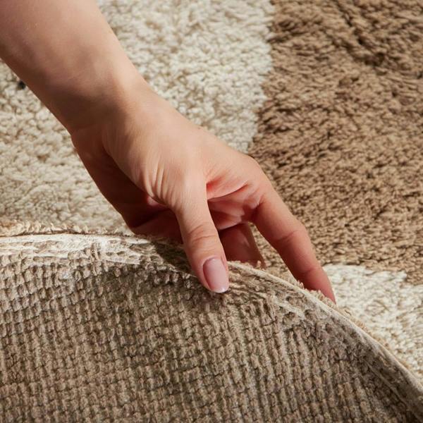 Hand touching a textured brown carpet