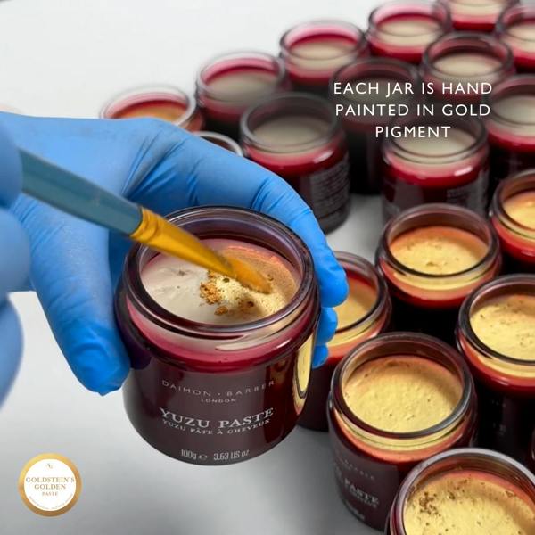 Hand painting gold into a Goldstein's Golden Paste jar with text about gold pigment.