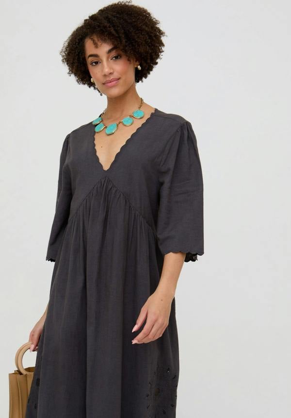 Woman wearing a dark gray dress with a plain background