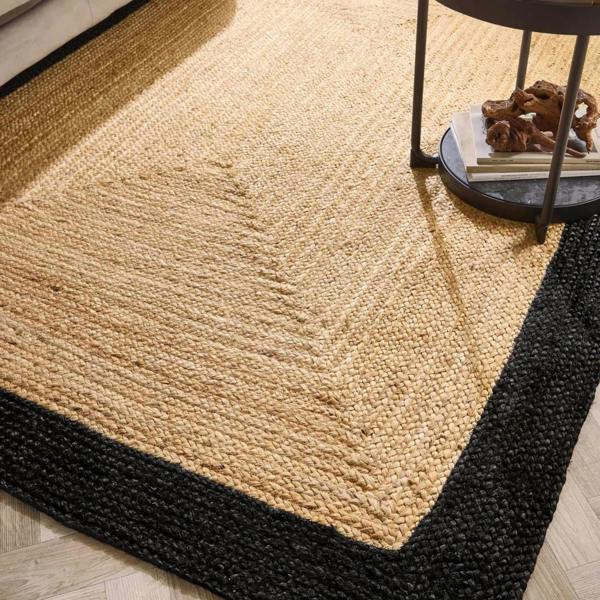 Beige jute rug with black border on a wooden floor
