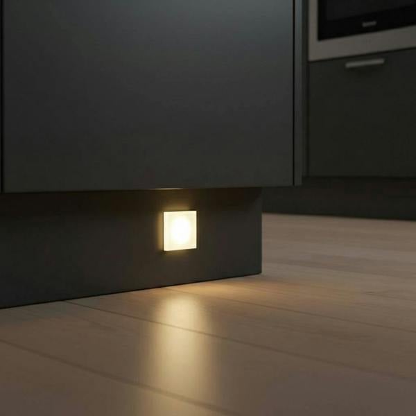 square LED plinth light mounted at low level in a grey kitchen plinth