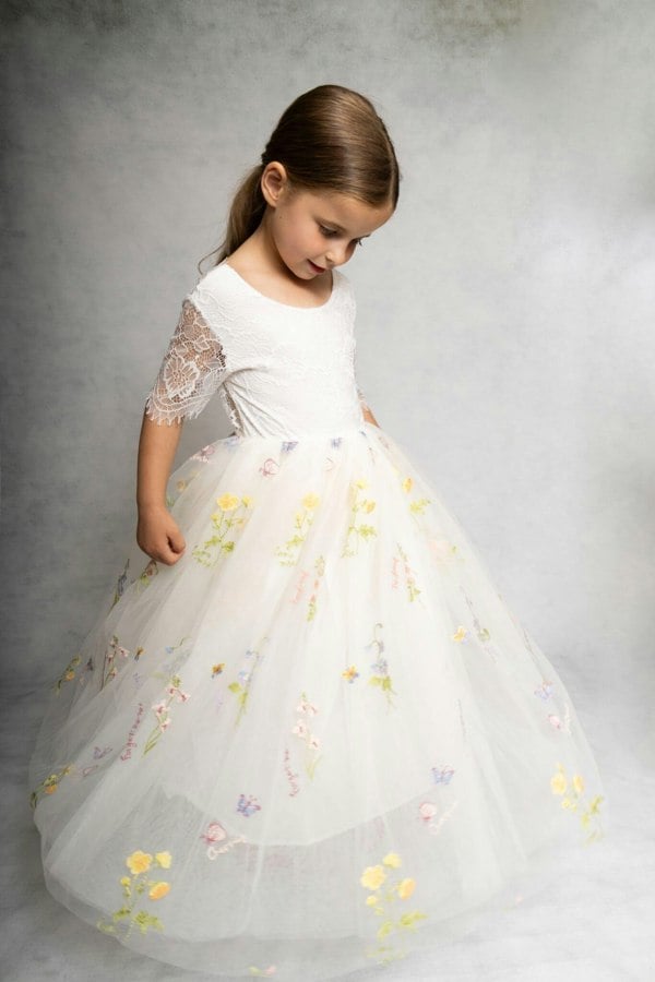 Young girl wearing a white floral dress against a gray background