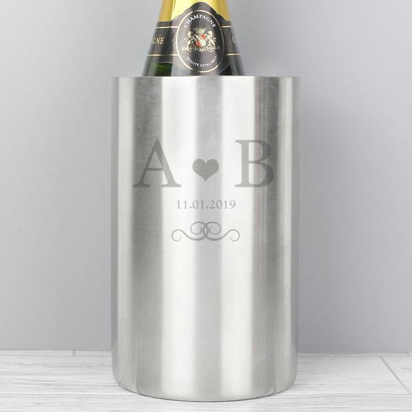 Close up of a brushed stainless steel wine cooler engraved with initials A and B, a heart, and a date, holding a bottle of champagne.