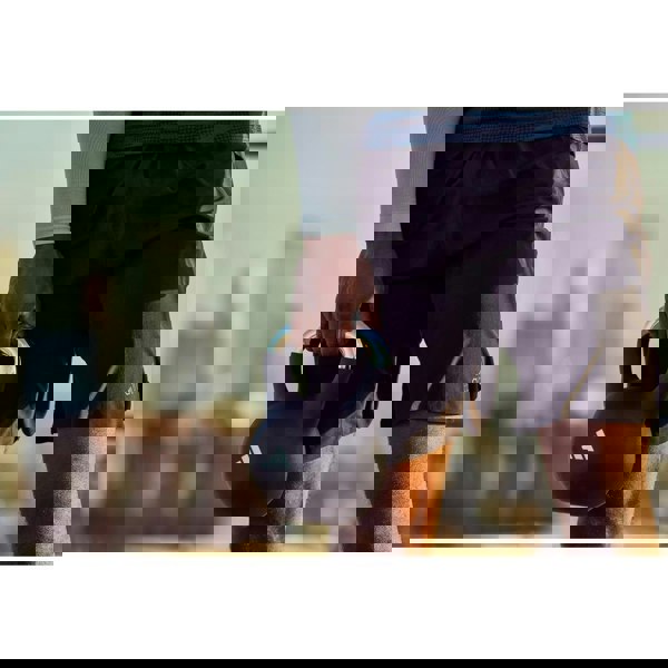 Person holding a black kettlebell with a blurred cityscape background