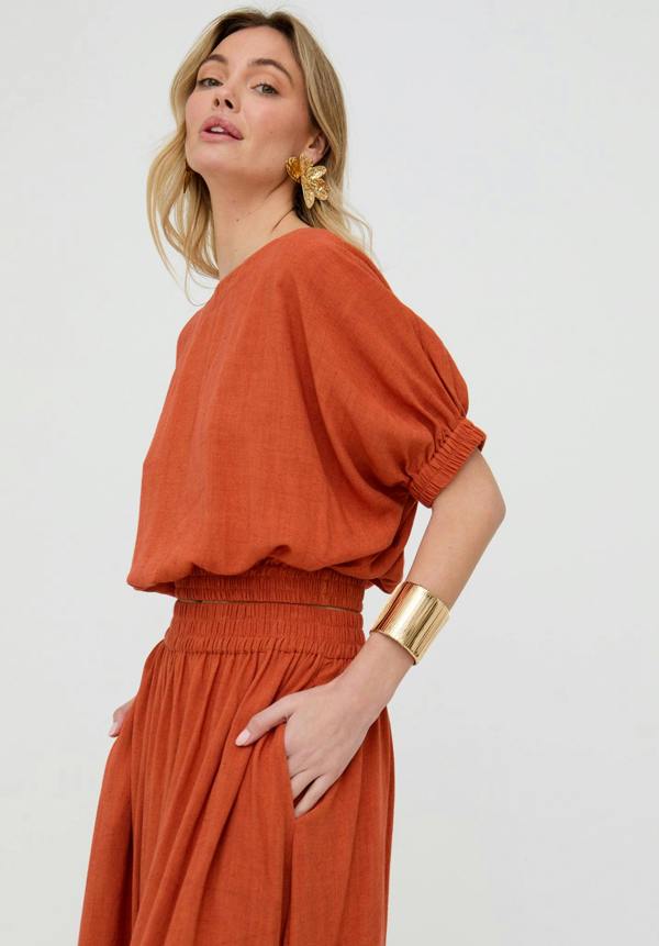 Woman wearing a rust-colored outfit on a white background