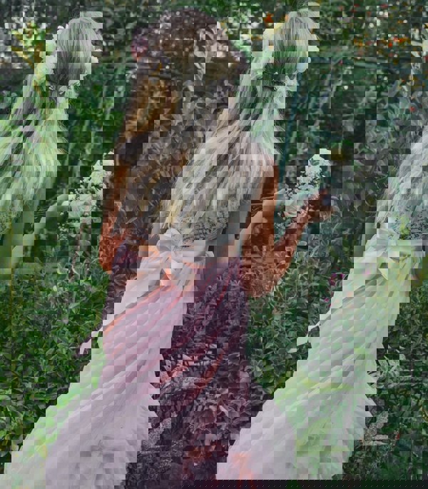 girl with headband and bouquet, standing in a garden.