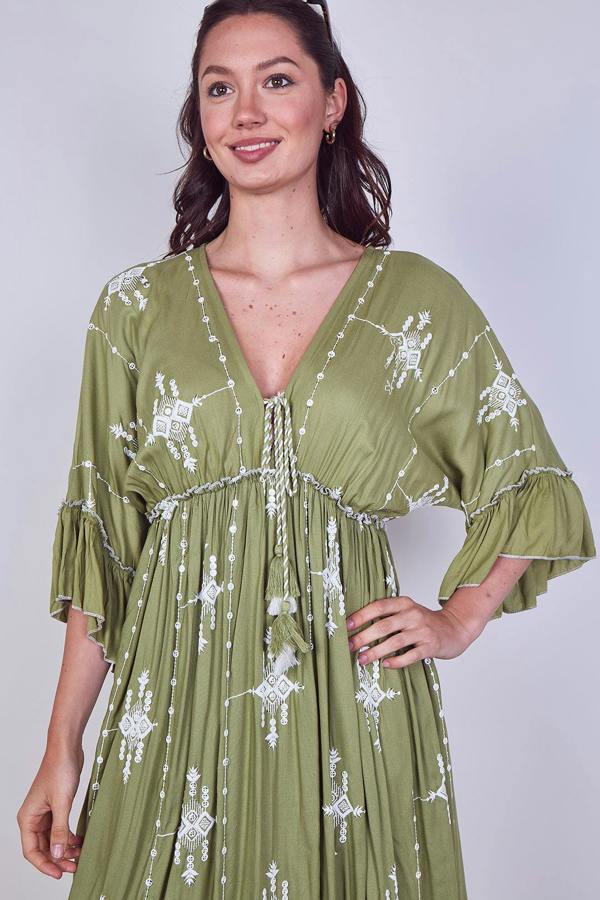 Woman wearing a green dress with white patterns against a plain background