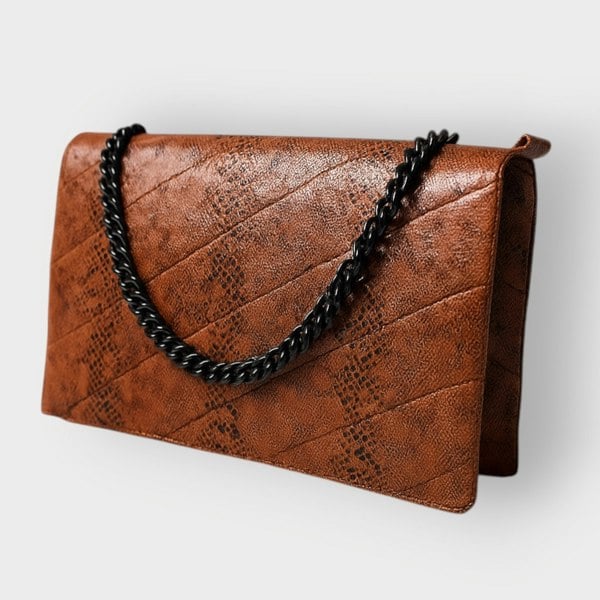 Brown textured clutch bag with a black chain strap on a light gray background