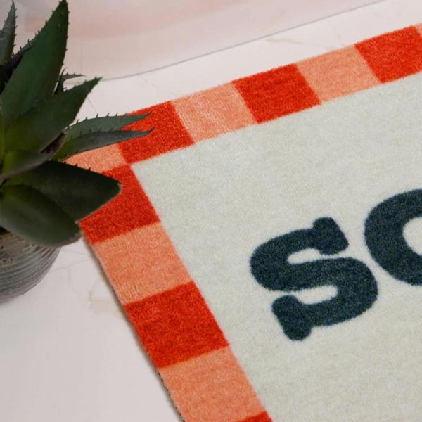 Doormat with red and white checkered border and 'Sole' branding on a light surface.