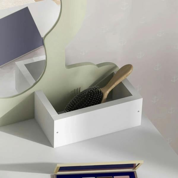 White vanity storage bin with hairbrush and comb on lower shelf