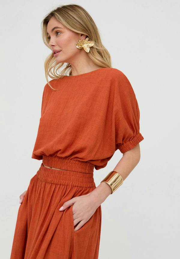 Woman wearing a rust-colored outfit with a plain background