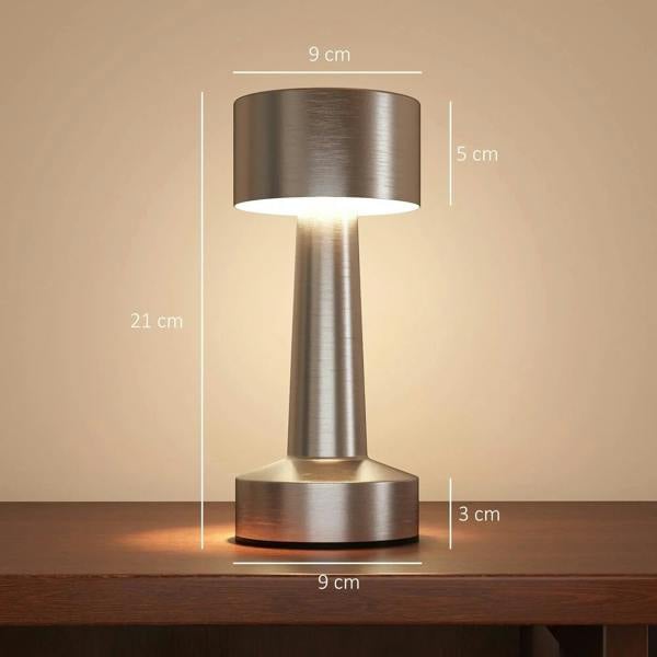 Silver cordless table lamp with lit cylindrical shade and stacked round metal base