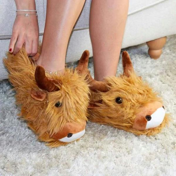 A pair of fluffy brown Highland cow slippers being worn on a carpeted floor.
