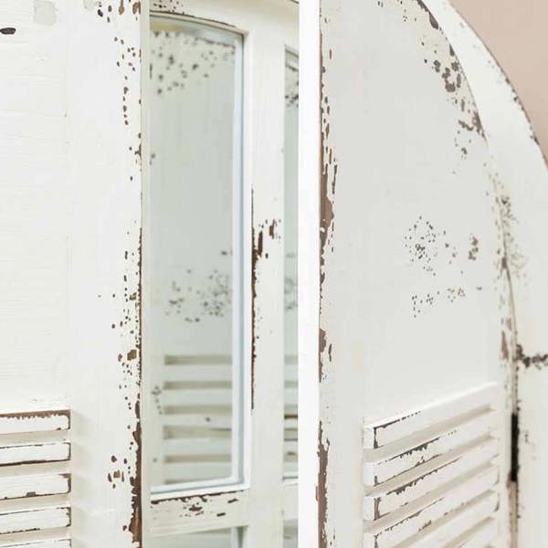 A close-up view of the arched curved top of the white weathered Château window mirror with partially open shutters.