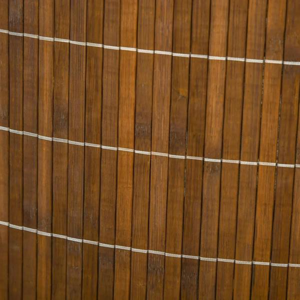 Close-up of brown bamboo slats on laundry hamper with white stitched trim