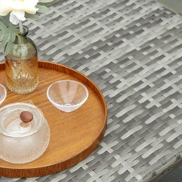 Grey woven PE rattan tabletop edge with light wood rim, with glass items
