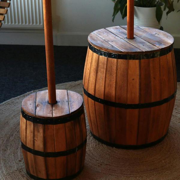 Two natural wood barrel tables with dark metal bands and umbrella pole tops