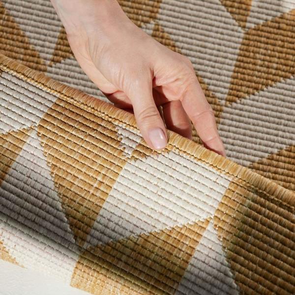 Hand touching a textured brown and beige patterned fabric