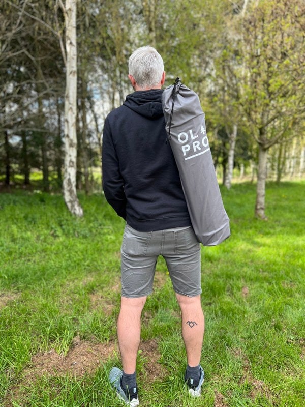 An image of an adult male carrying the Folding Camp Table from OLPRO over there shoulder.