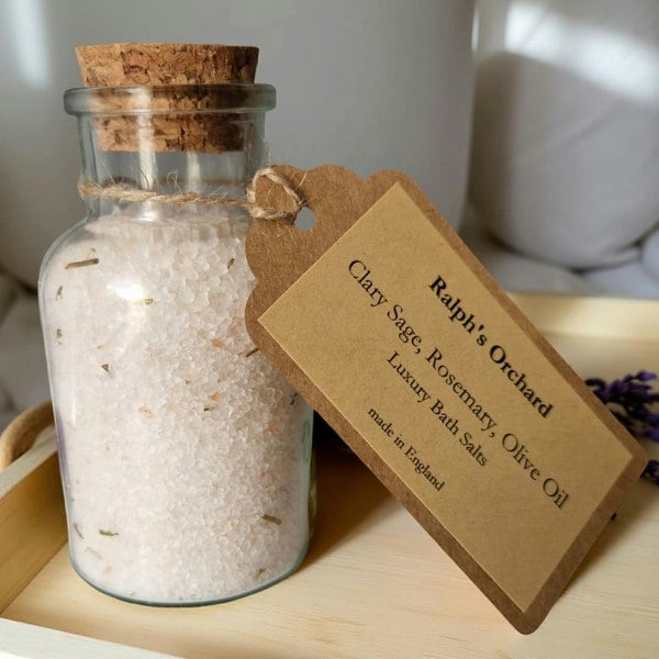 Glass jar of bath salts with a label on a wooden tray