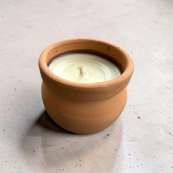 Candle in a terracotta pot on a light surface