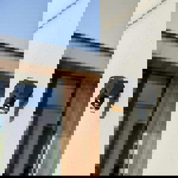 black outside spotlight wall light mounted on a concrete wall outside a modern house