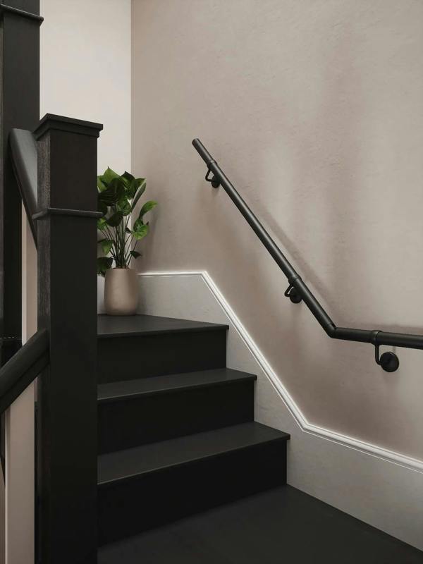 Staircase with black handrail and steps, beige wall, and plant decoration.