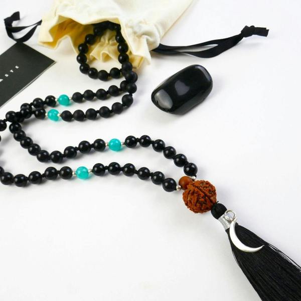 Kati Kaia Black Obsidian Crystal Necklace with turquoise accents and a tassel, displayed with a pouch