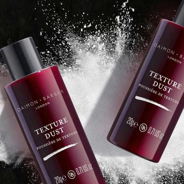 Two bottles of Texture Dust on top of white powder on a black background