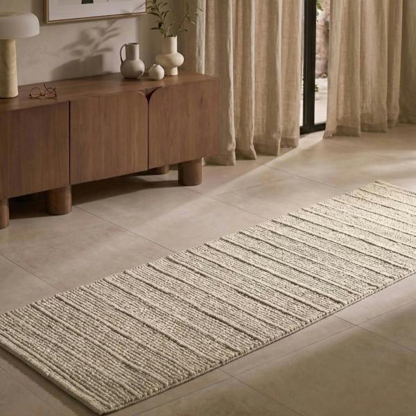 Long rectangular rug on a tiled floor in a room with wooden furniture and curtains.
