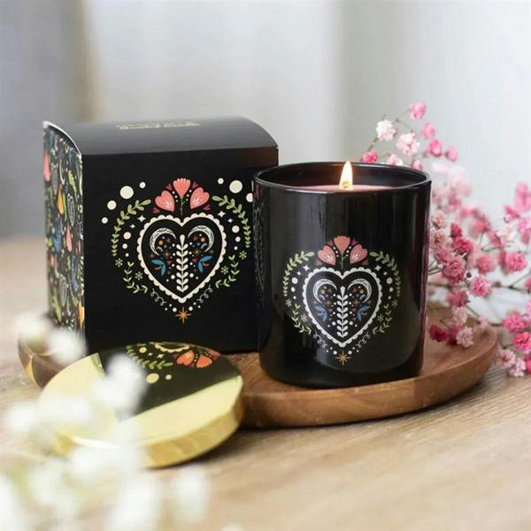 Black scented candle jar with heart floral pattern and lit wick