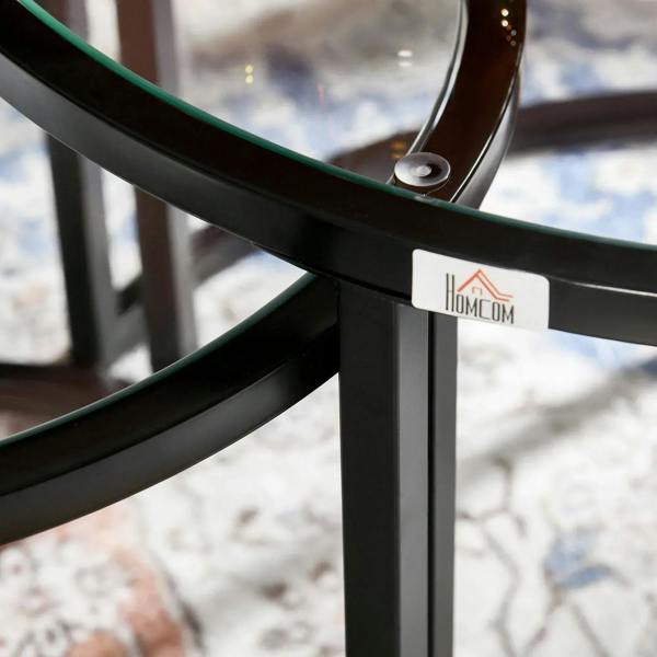 Close-up of black glass-top table edge with a logo label on the metal rim.
