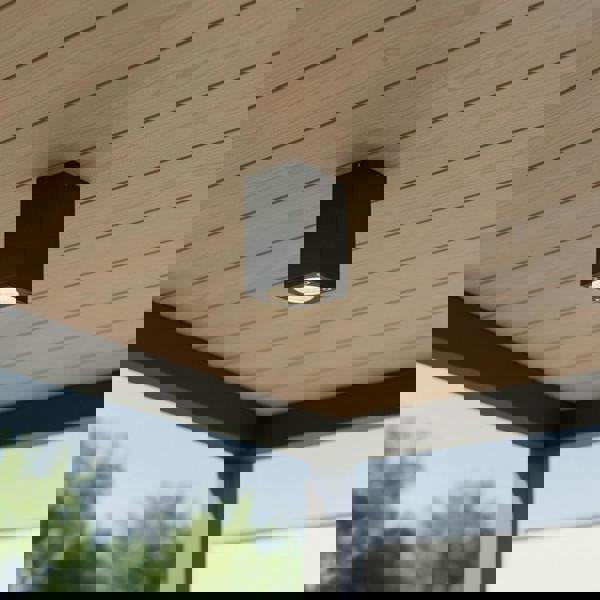 black surface mount exterior soffit light mounted on a wooden outdoor ceiling 