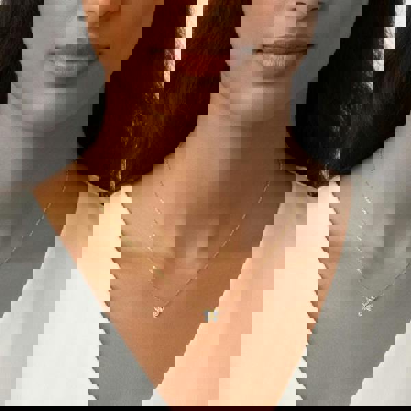 Close-up of a woman wearing a gold necklace with a butterfly pendant. 9mm butterfly pendant necklace by BLOOMTINE, crafted in tarnish-resistant gold over sterling silver with sustainable moissanite stones. Featuring an adjustable 14.5 to 16.5-inch chain for a bespoke fit, this dainty gold necklace is an ethical diamond alternative for meaningful gifting