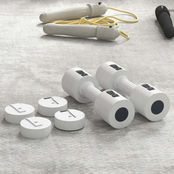 White adjustable dumbbells with removable discs and spare handle pieces on a tray