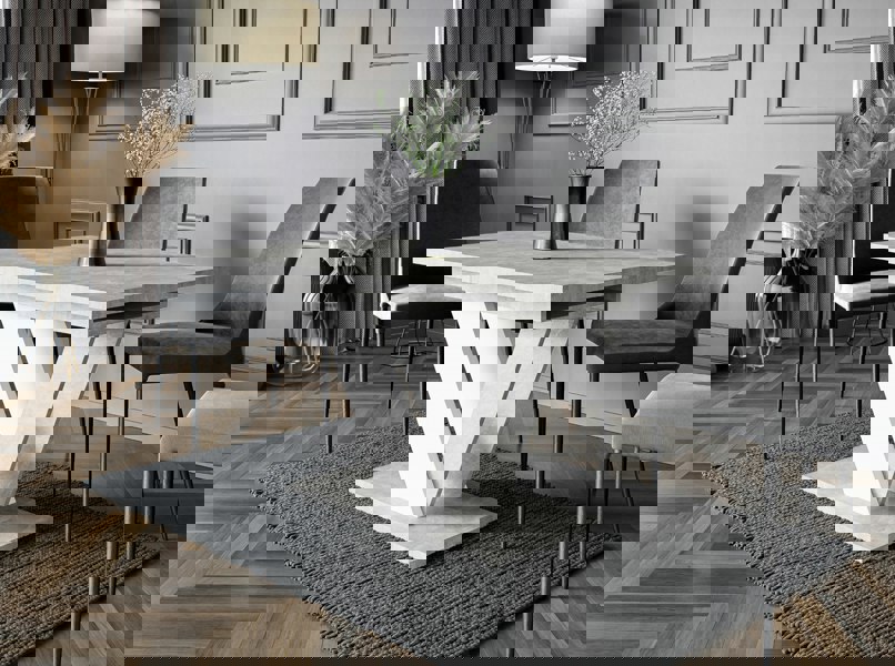 Modern dining room with a concrete table and gray chairs on a patterned rug.