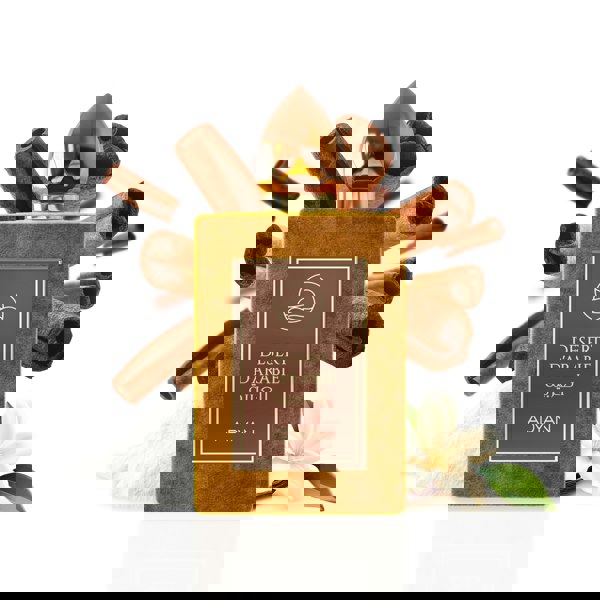 Perfume bottle labeled 'Desert d'Arabie' by Adyan with cinnamon sticks and vanilla flowers on a white background