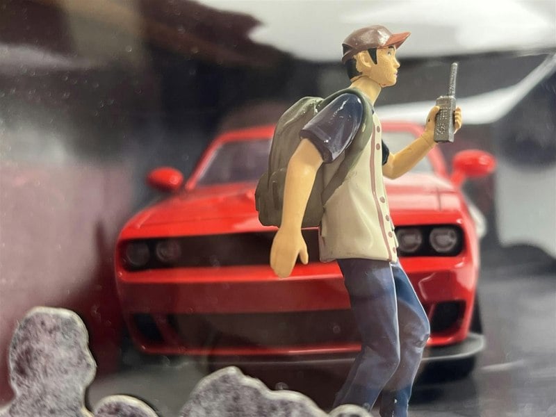 a toy figure of a man walking with a red car