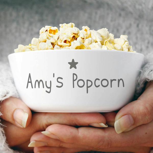 A white plastic bowl filled with popcorn, custom printed with a grey star accent and personalised name lettering.