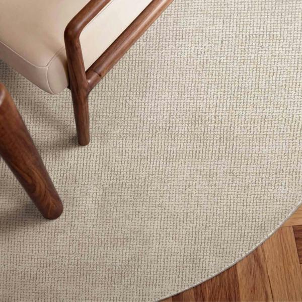 Close-up of a textured beige rug with wooden furniture legs.