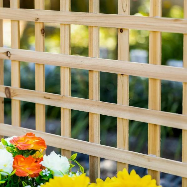 Wood trellis slat grid with nearby blooming flowers at the base
